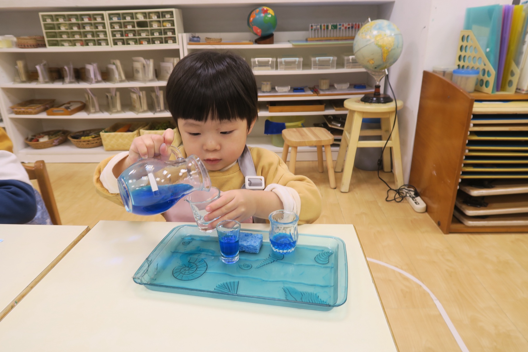 孩子倒水並照顧操作材料