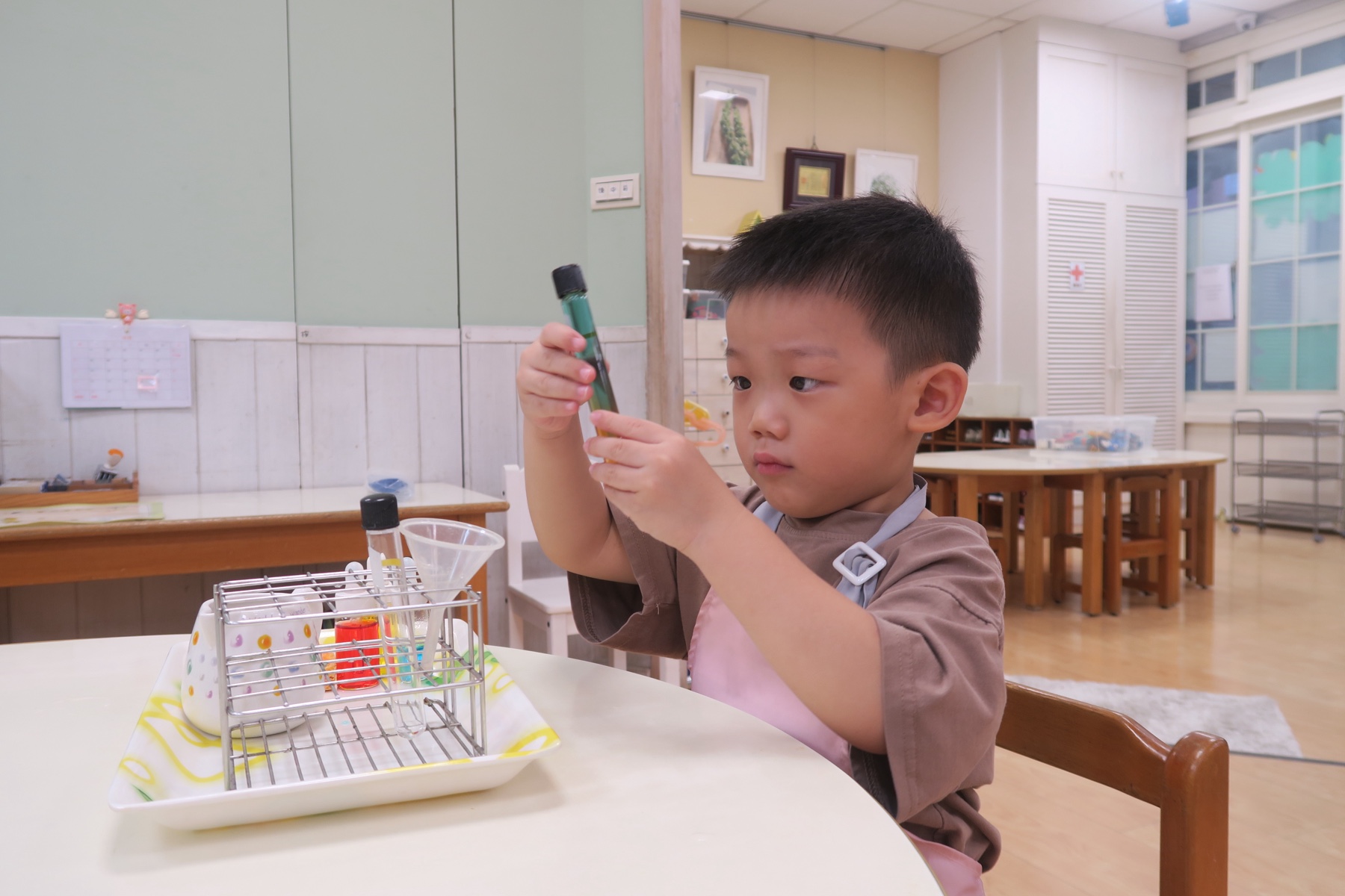 孩子專注觀察手中的瓶子與教具