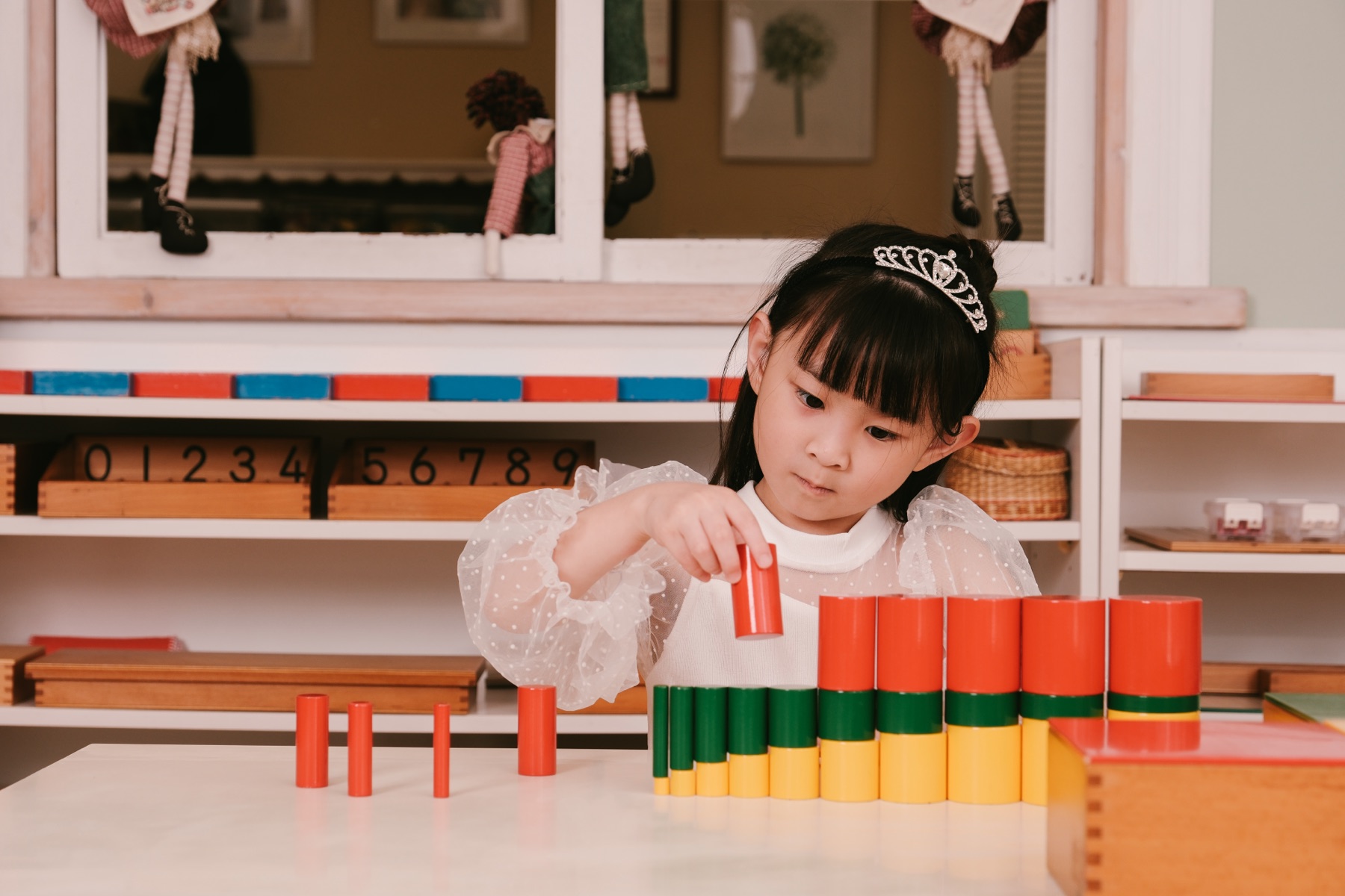 孩子專注操作彩色圓柱體教具