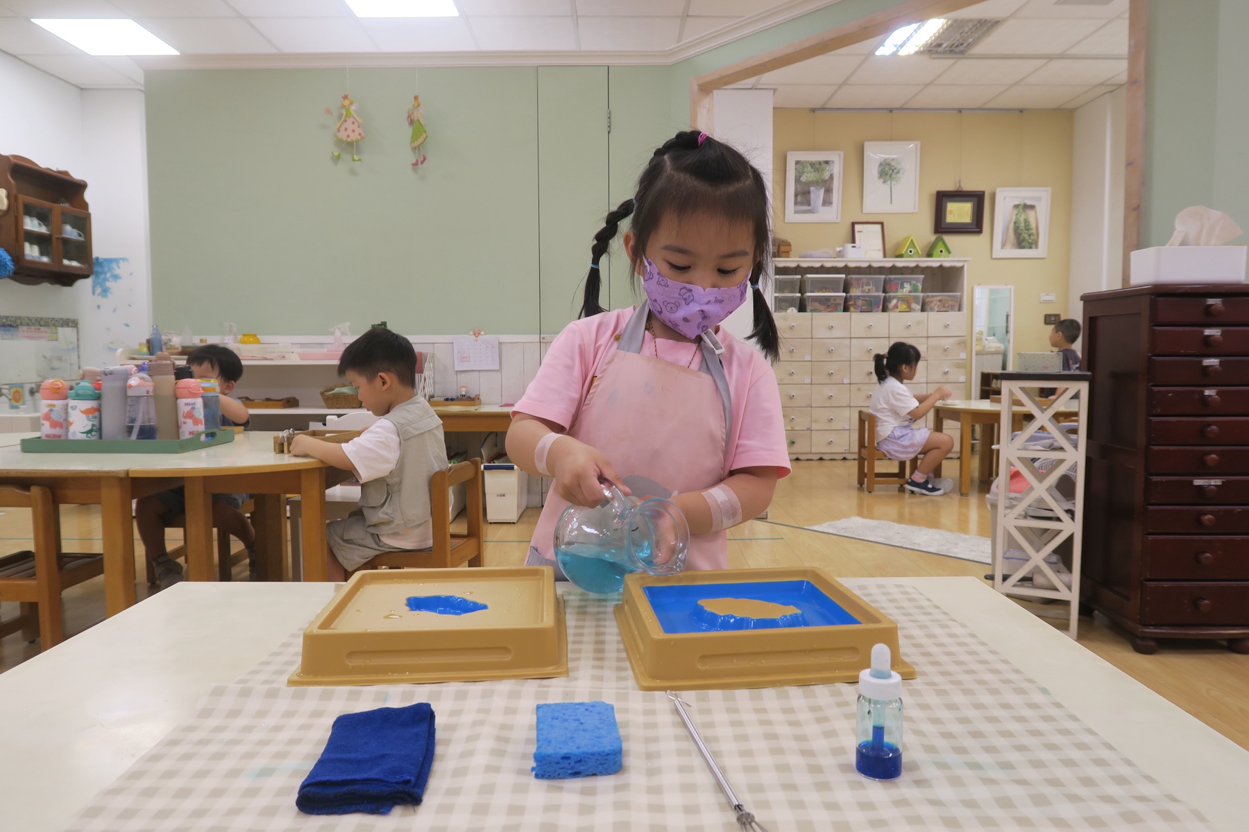 孩子在教室中練習倒水工作